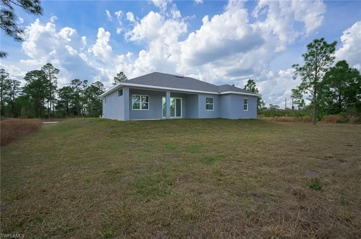 Rear view of house featuring stucco siding, a patio area, and a lawn