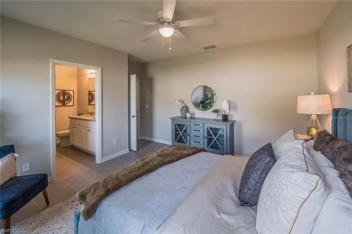 Bedroom with a ceiling fan, ensuite bathroom, and light tile patterned flooring