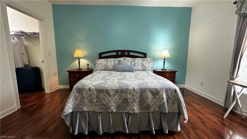 Bedroom with dark hardwood / wood-style floors, a closet, and a spacious closet