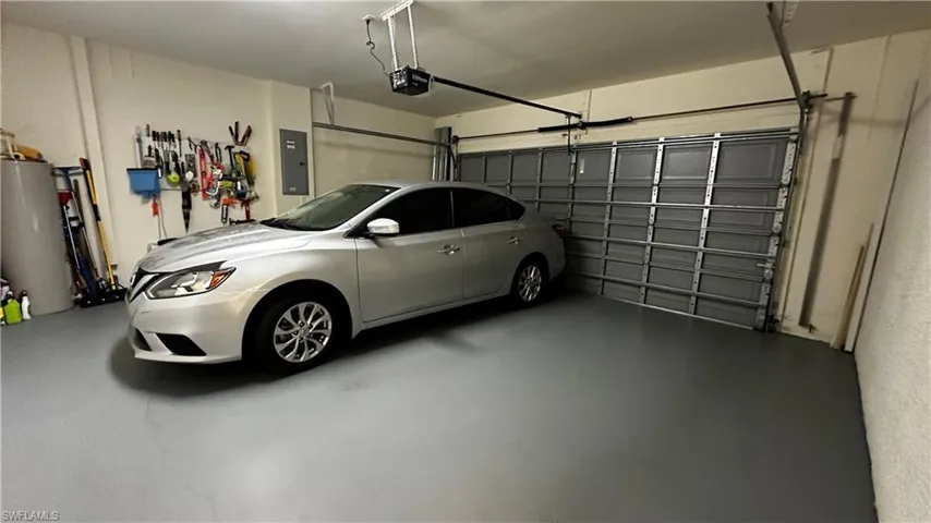 Garage with a garage door opener, gas water heater, and electric panel