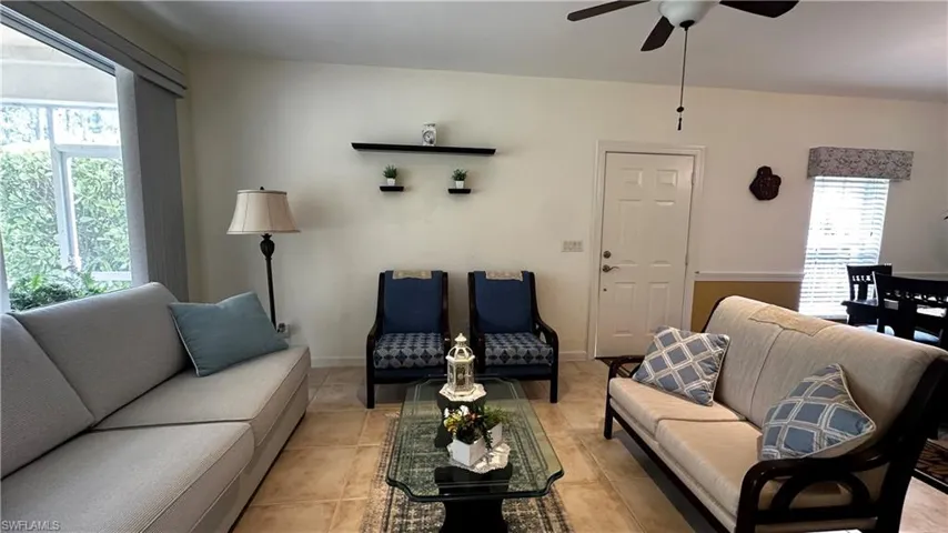 Living room with ceiling fan, tile patterned flooring, and plenty of natural light