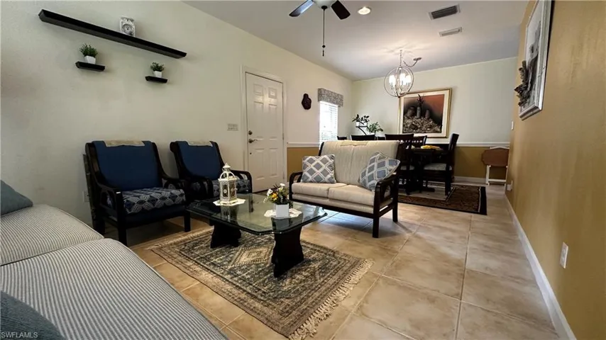 Living room featuring light tile patterned flooring and ceiling fan with notable chandelier