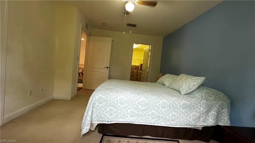 Bedroom with light colored carpet, ensuite bathroom, and ceiling fan