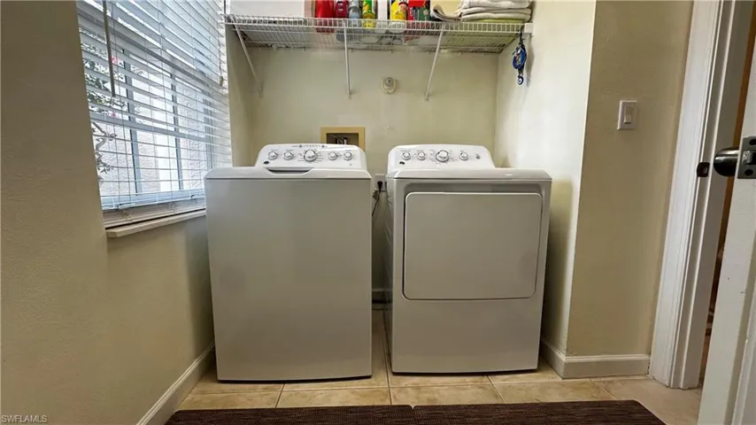 Washroom featuring washing machine and clothes dryer and light tile patterned floors