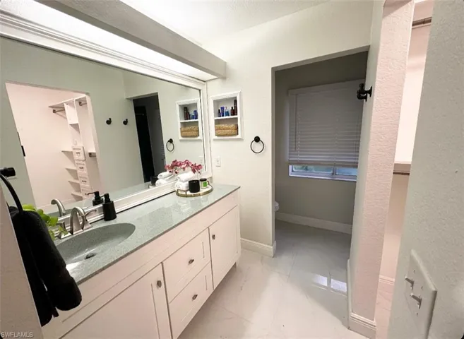 Bathroom with dual vanity, tile flooring, and toilet