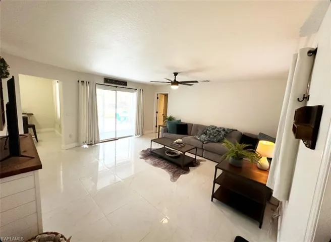 Living room featuring tile flooring, ceiling fan, and a textured ceiling
