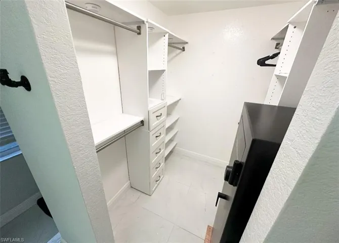 Walk in closet with light tile floors