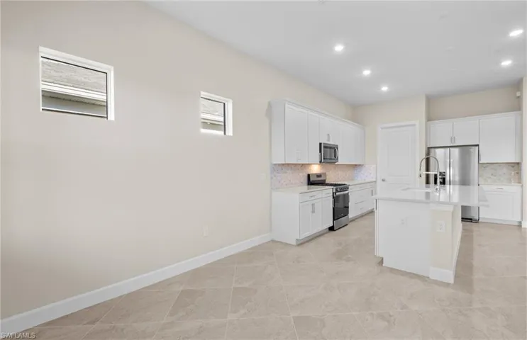 Kitchen with stainless steel appliances, white cabinetry, tasteful backsplash, and recessed lighting