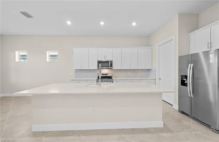 Kitchen featuring stainless steel appliances, white cabinetry, decorative backsplash, and recessed lighting