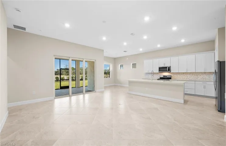 Kitchen with white cabinets, a center island with sink, stainless steel appliances, open floor plan, and recessed lighting