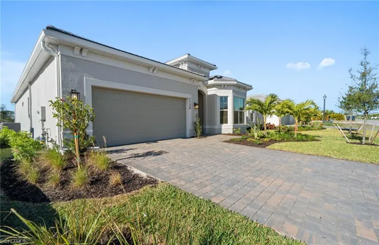 View of front of property with stucco siding, decorative driveway, an attached garage, and a front yard