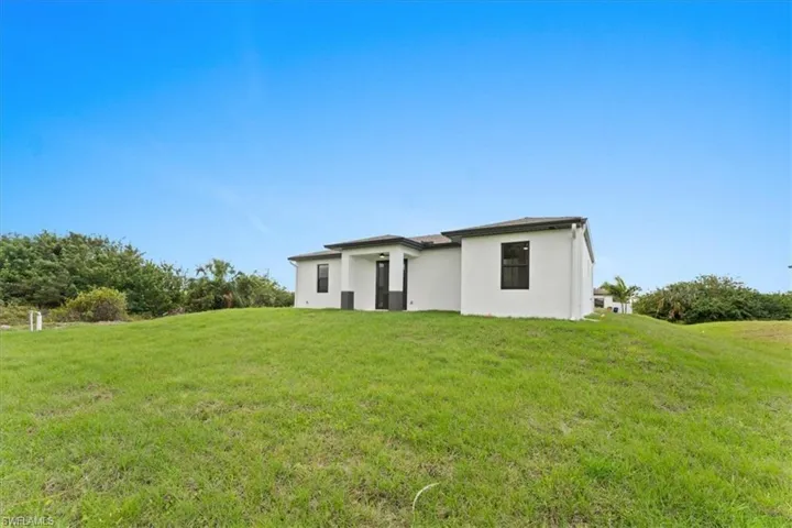Back of property featuring a yard and stucco siding