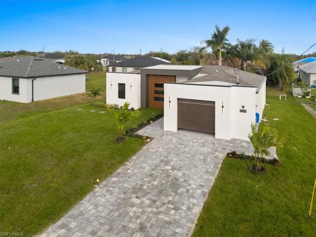 View of front of house with a front lawn, decorative driveway, an attached garage, and stucco siding