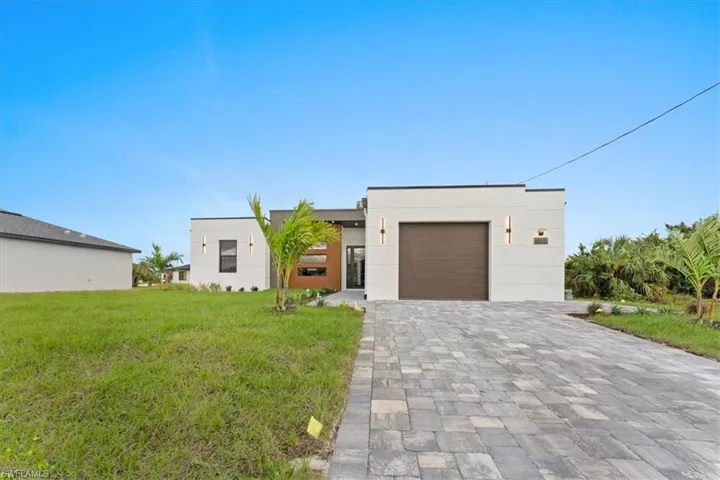 Contemporary house with a garage, decorative driveway, and a front yard