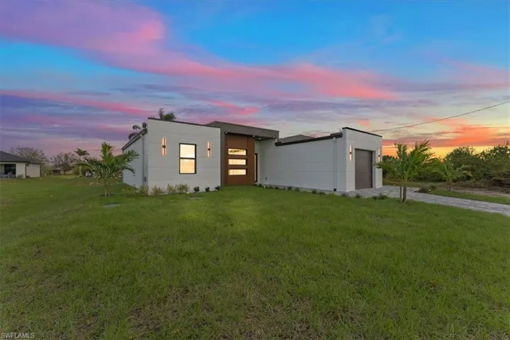 Modern home featuring a garage, concrete driveway, and a yard