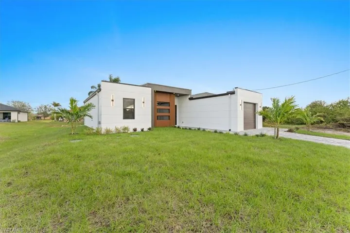 View of front of home with a garage, concrete driveway, and a front lawn