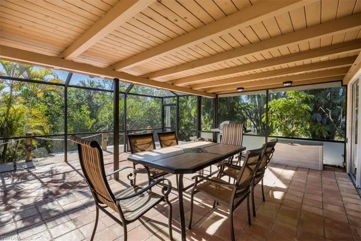Sunroom / solarium with beam ceiling and outdoor dining space