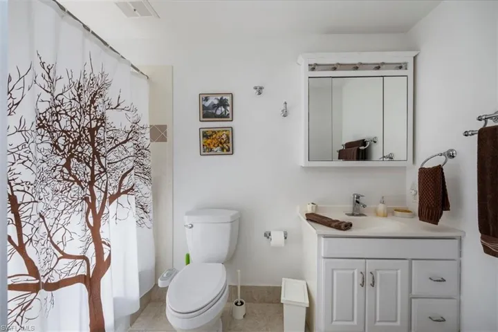 Bathroom featuring a shower with curtain, visible vents, vanity, and toilet