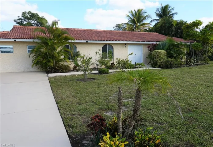 Ranch-style home featuring a tiled roof, a front lawn, and stucco siding