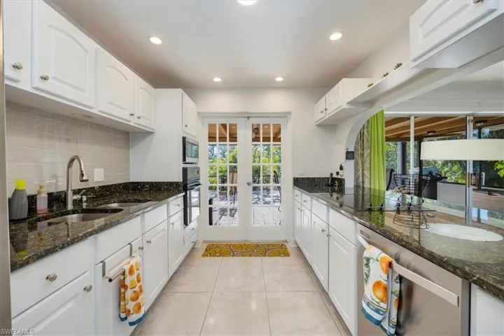 Kitchen featuring french doors, a sink, backsplash, black appliances, and light tile patterned floors