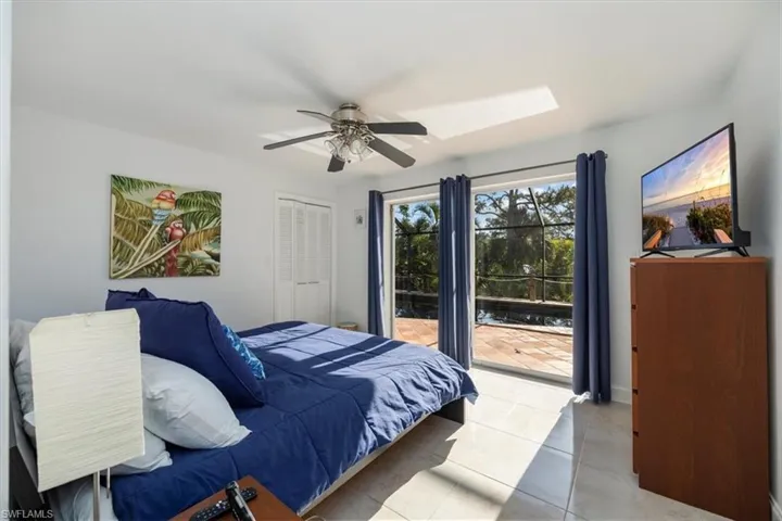 Bedroom featuring ceiling fan, light tile patterned flooring, a closet, a skylight, and access to outside