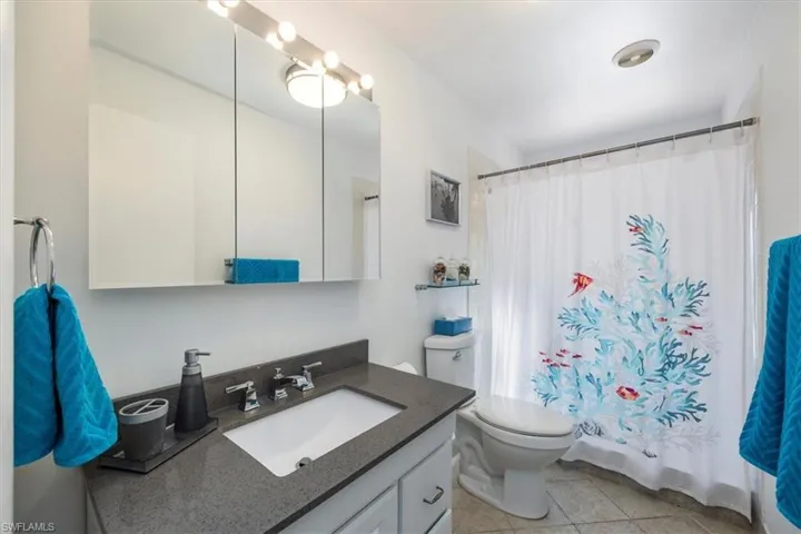Full bath with vanity, tile patterned flooring, a shower with shower curtain, and toilet