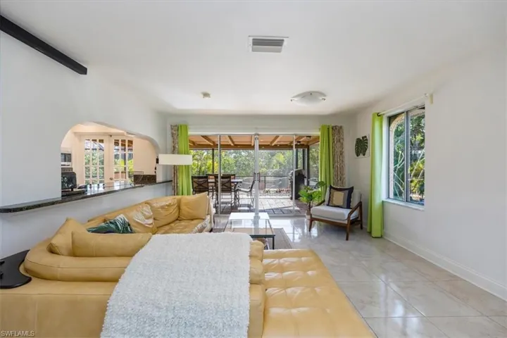 Living area featuring visible vents, baseboards, arched walkways, and a sunroom
