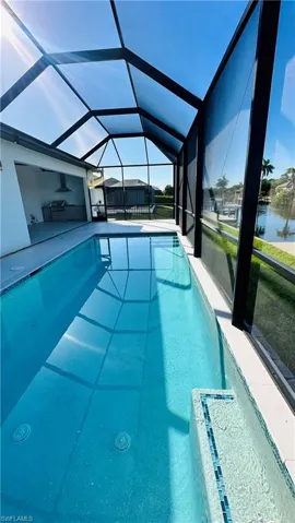 Screened-in swimming pool with an integrated spa featuring mosaic tile