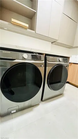 Integrated washer and dryer, light-colored countertops, built-in upper cabinetry, and recessed lighting