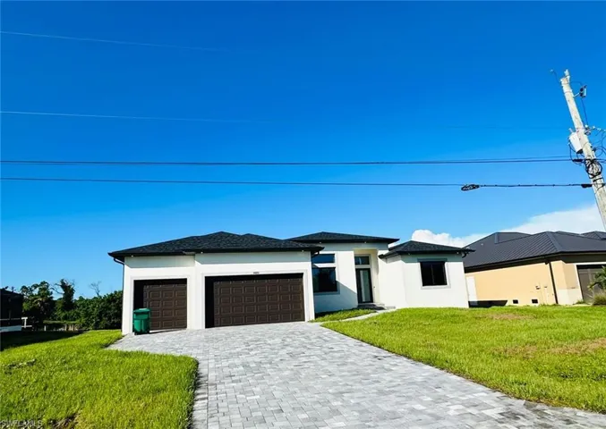 Contemporary stucco exterior with a dark shingle roof, two-car garage, paver driveway, and a covered entry