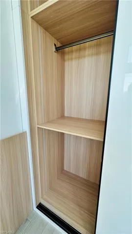Built-in closet with wood-finish interior, integrated shelving, and a hanging rod