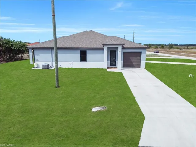 View of front of house featuring stucco siding, driveway, a shingled roof, and a front lawn