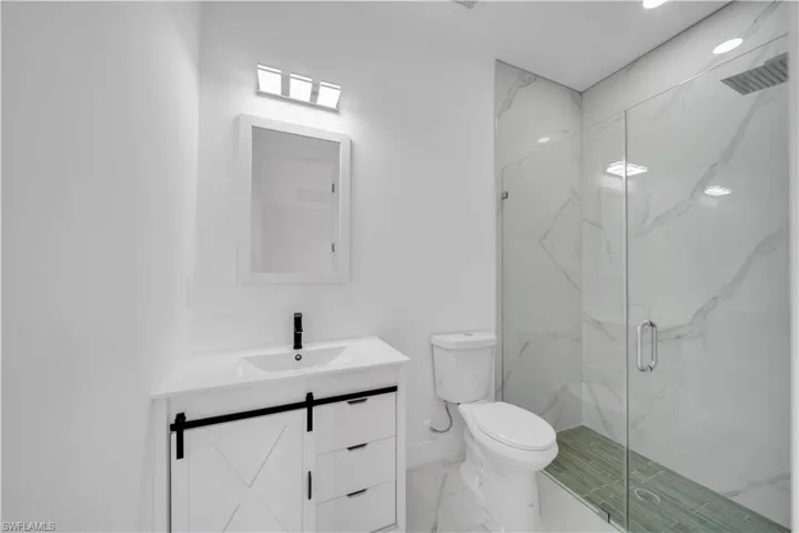 Full bathroom featuring a marble finish shower, vanity, and marble finish flooring