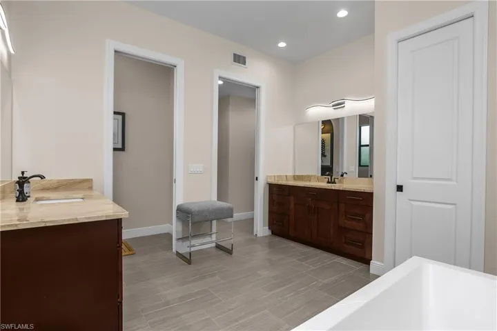 Dual vanities, custom lighting, and soaking tub in primary bath.