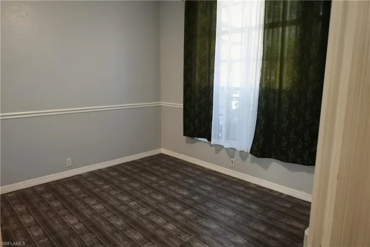 Interior room with wood-finish flooring, two-tone walls, and a window