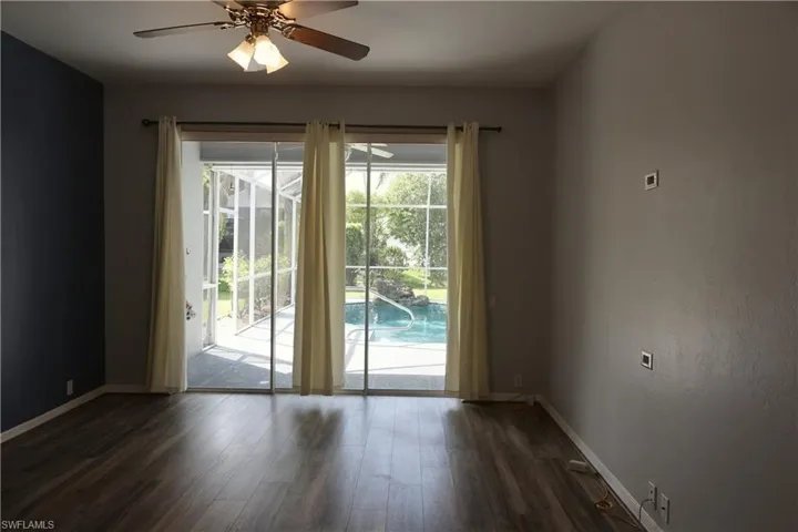 Spacious room featuring wood-finish flooring, a ceiling fan with integrated lighting, and a large sliding glass door