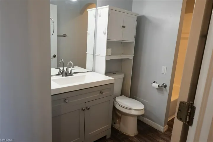 Bathroom featuring a gray vanity with an integrated sink, brushed nickel faucet, and a large wall mirror