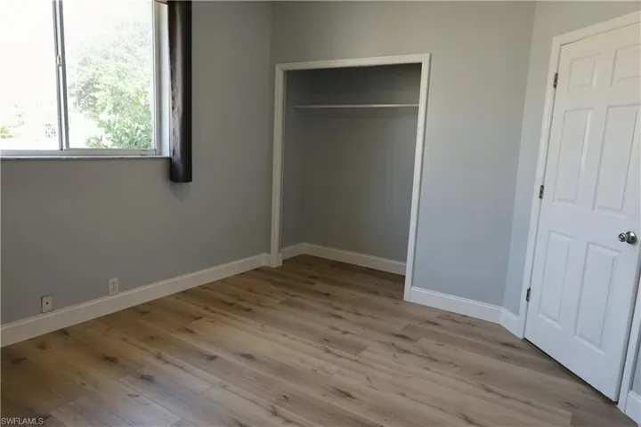 Wood-finish flooring with white baseboards and light gray walls