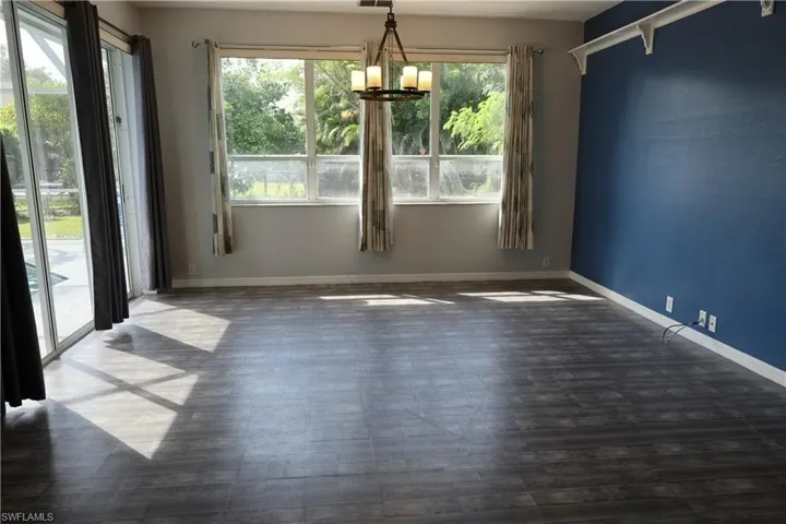Spacious interior featuring wood-finish flooring, a contemporary chandelier, large windows, and sliding glass doors