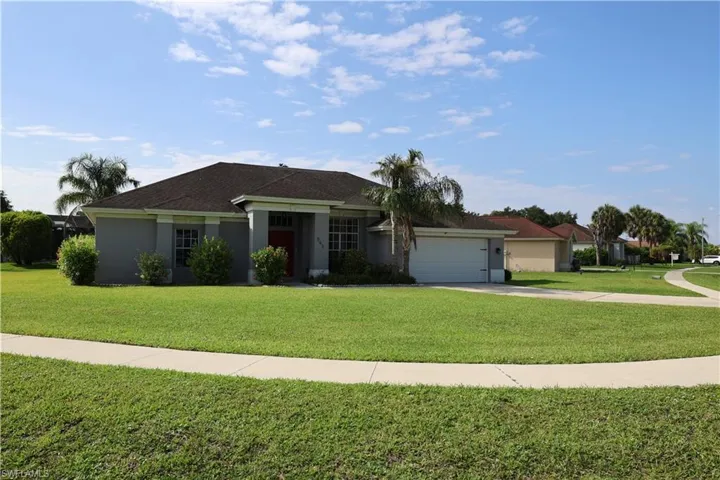 Single-story home featuring a gray exterior, a dark shingle roof, an attached two-car garage, mature landscaping, and a manicured front lawn
