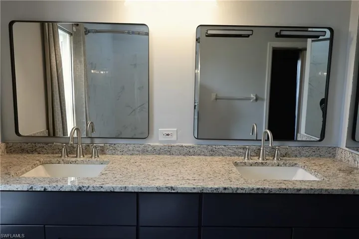 Dual sink vanity with stone-finish countertops and dark cabinetry
