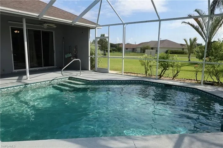 Screened-in swimming pool featuring integrated steps, a poolside handrail, and a surrounding deck