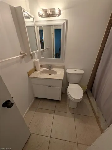 Full bath featuring vanity, curtained shower, and light tile patterned flooring