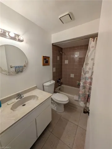 Guest bathroom featuring shower / bath combination with curtain, vanity, and light tile patterned flooring