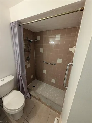 Full bathroom featuring a shower stall and light tile patterned floors