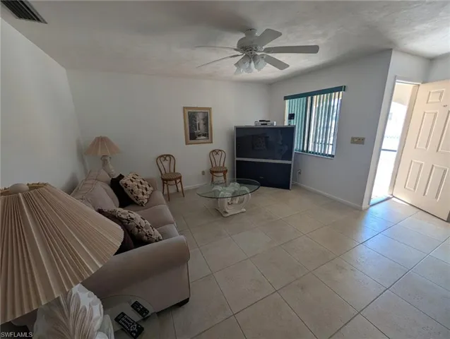 Living area featuring light tile patterned floors and a ceiling fan