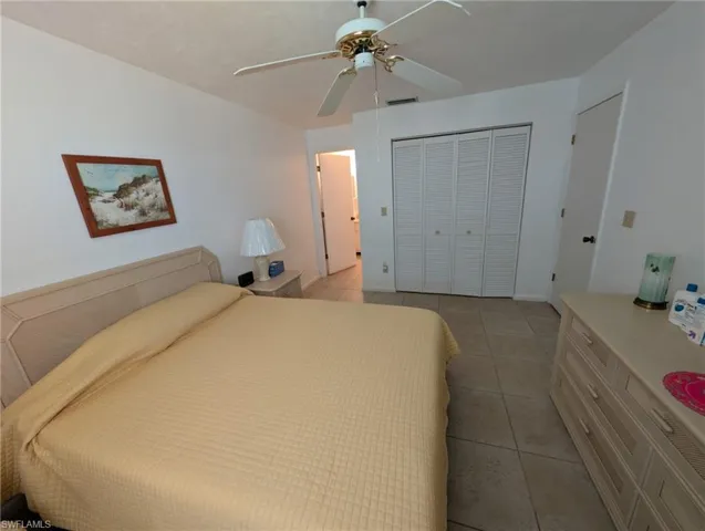 Bedroom with light tile patterned floors, a closet, and ceiling fan