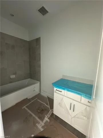 Bathroom featuring tiled shower / bath and vanity