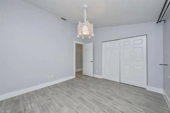 Unfurnished bedroom featuring light wood finished floors, a closet, and lofted ceiling