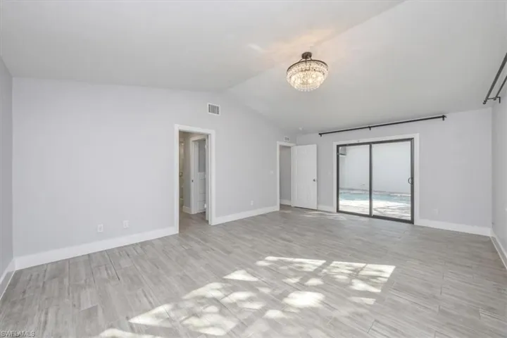 Unfurnished room featuring lofted ceiling, wood finish floors, and a chandelier